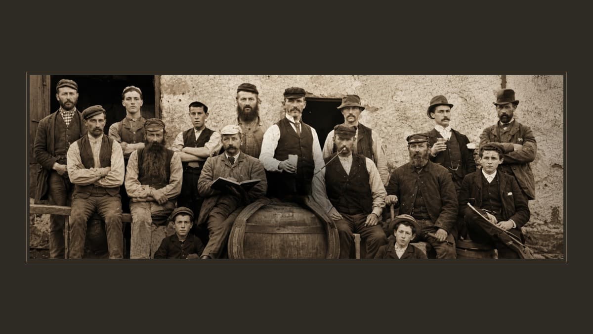 Sepia group portrait of men and boys in caps and waistcoats before a rough plaster wall, beside a wooden cask; one holds a book, another a pipe and another a violin